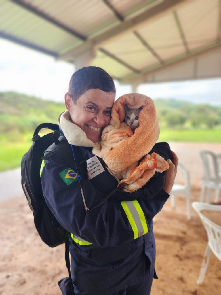 Veterinária Bianca do GRAD Brasil segurando um gato enrolado em cobertor após atendimento, durante missão.